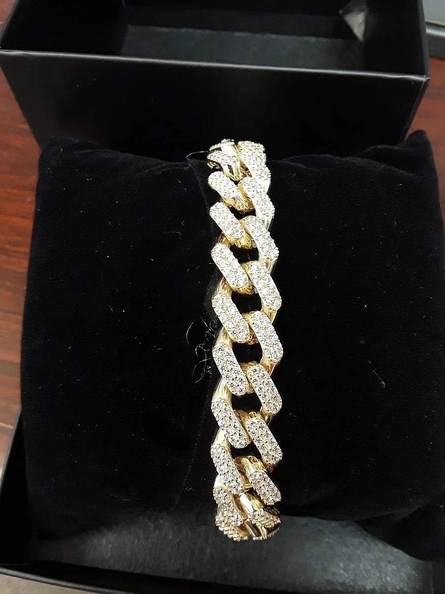 Iced-out gold Cuban link bracelet on a black velvet display